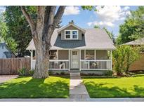Charming home featuring a cozy front porch, well-manicured lawn, and a large tree providing shade at 3976 S Washington St, Englewood, CO 80113