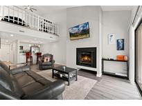 Spacious living room features a fireplace, vaulted ceiling, and loft overlooking a modern open kitchen at 1160 S Monaco Pkwy # 6, Denver, CO 80224