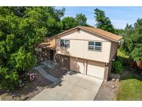 Two-story home with an attached two-car garage and mature trees in a well-kept front yard at 6411 W 82Nd Dr, Arvada, CO 80003