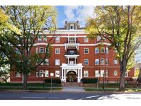 Three-story red brick condo building with mature trees, white trim, and inviting entrance at 836 E 17Th Ave # 2B, Denver, CO 80218