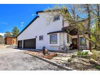 Charming home exterior boasts a two-car garage and a welcoming front porch with rustic decor at 1673 Woodmoor Dr, Monument, CO 80132