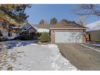 Brick ranch home with attached garage and snow-covered yard at 6055 W Warren Pl, Lakewood, CO 80227
