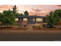 Charming brick home featuring a landscaped front yard, solar panels, and blue door at 5455 E Iowa Ave, Denver, CO 80222