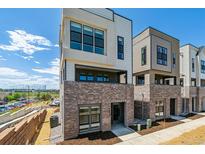 Modern townhome featuring a brick facade, balcony, and large windows providing ample natural light at 11493 E Briarwood Cir, Centennial, CO 80112