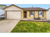 Charming brick home featuring a well-maintained lawn and a cozy seating area near the front entrance at 2104 Vineyard Dr, Castle Rock, CO 80104