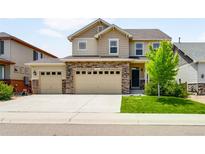 Charming two-story home featuring a three-car garage, stone accents, and manicured lawn at 1339 Sidewinder Cir, Castle Rock, CO 80108