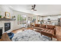 Spacious living room with a brick fireplace, ceiling fan, and a seamless transition to the modern kitchen at 24356 E Powers Ave, Aurora, CO 80016