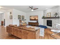 Cozy living room with fireplace, ceiling fan, wood floors, and exposed brick at 24356 E Powers Ave, Aurora, CO 80016