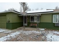 Green, single-story home with a covered front porch and a bench, solar panels, and some snow at 1134 Del Mar Pkwy, Aurora, CO 80010