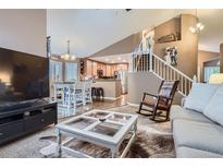Open concept living room showcases seamless flow to the kitchen and a staircase with white railing at 16200 Hedgeway Dr, Parker, CO 80134