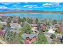 Stunning aerial view of lakeside homes with mature trees and beautiful lake and mountain backdrop at 3331 Lakeview Cir, Longmont, CO 80503
