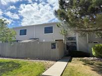 Charming townhome exterior with a fenced yard, lush green grass, and a well-maintained walkway at 7705 W 87Th Dr, Arvada, CO 80005