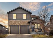 Charming two-story home featuring stone accents, a two-car garage, and a cozy covered front porch at 9084 Ellis Way, Arvada, CO 80005