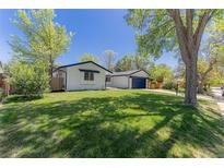 Well-maintained home with a green lawn and mature trees, showcasing curb appeal at 1486 S Kingston St, Aurora, CO 80012
