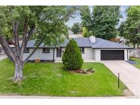 Charming single-story home with a manicured lawn, lush trees, and a modern dark-colored garage door at 210 E Graves Ave, Centennial, CO 80121