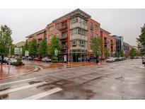 Upscale brick condominium building with modern architectural details on a wet city street at 191 Clayton Ln # 402, Denver, CO 80206