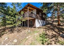 Charming cabin with a large wooden deck surrounded by trees and natural landscape at 7105 Flagstaff Rd, Boulder, CO 80302
