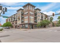 Corner view of a modern brick apartment building with pedestrian crosswalk and street signage at 1441 Central St # 209, Denver, CO 80211