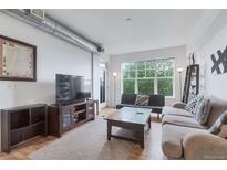 Bright living room with hardwood floors, modern furnishings and a large window overlooking the city at 1441 Central St # 209, Denver, CO 80211