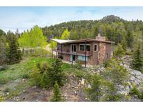 Stunning home with brick and stone exterior, surrounded by lush greenery and mature trees on a large lot at 401 Highway 72, Golden, CO 80403