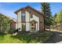 Charming two-story home with brown and white painted exterior, surrounded by green foliage and a quaint fence at 27124 Sun Ridge Dr, Evergreen, CO 80439