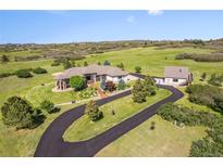 Expansive ranch-style home with a detached garage, a long drive, and mature landscaping on a rolling, green lawn at 3358 Castle Butte Dr, Castle Rock, CO 80109