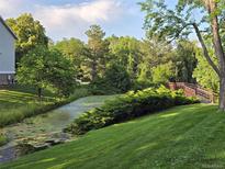 Beautiful pond with a walking bridge surrounded by lush greenery and mature trees at 850 W Moorhead Cir # 3F, Boulder, CO 80305