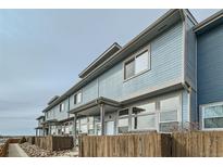 Blue two-story townhomes with wooden fences and well-maintained landscaping create a welcoming curb appeal at 12032 Monaco St, Brighton, CO 80602