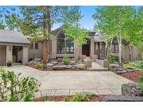 Charming home with a bridge entrance, beautiful landscaping, and mature trees at 29432 Camelback Ln, Evergreen, CO 80439