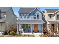 Charming two-story home showcasing a covered front porch with stylish seating and an eye-catching orange front door at 9768 E 62Nd Dr, Denver, CO 80238