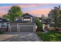 Charming two-story home featuring a three-car garage, manicured lawn, and lovely landscaping at sunset at 16342 Parkside Dr, Parker, CO 80134