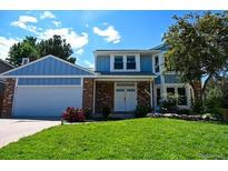 Inviting two-story home with a well-manicured lawn and a charming blue and brick facade at 4753 S Gar Way, Littleton, CO 80123