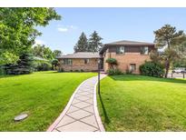 Charming brick home boasts a well-manicured lawn and inviting walkway, creating a warm curb appeal at 591 Nome St, Aurora, CO 80010