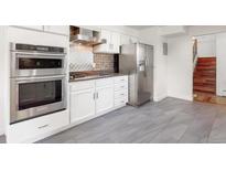 Modern kitchen with stainless steel appliances, white cabinets, and gray tile flooring provides a stylish space at 591 Nome St, Aurora, CO 80010
