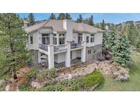 Stunning home with a patio, stone accents, lush landscaping, and a private balcony to take in the wooded views at 730 Summerwood Dr, Golden, CO 80401
