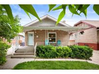 Charming brick home featuring a cozy front porch, landscaped yard, and a delightful light blue front door at 1532 Meade St, Denver, CO 80204
