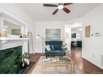 Bright living room with a modern ceiling fan, fireplace, decorative rug, and an accent chair at 1803 E 36Th Ave, Denver, CO 80205