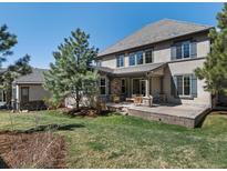 Exterior home view with a large backyard, covered patio and beautiful stone and stucco facade at 6877 Northstar Ct, Castle Rock, CO 80108