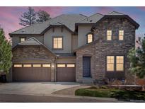 Elegant home featuring a stone facade, three-car garage, and beautiful architectural details at dusk at 6877 Northstar Ct, Castle Rock, CO 80108