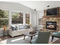 Comfortable living room featuring a stone fireplace, large windows, and ample natural light at 6877 Northstar Ct, Castle Rock, CO 80108