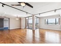 Bright living room features hardwood floors, ceiling fan, and sliding glass doors to a balcony with city views at 1551 Larimer St # 1803, Denver, CO 80202