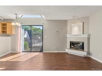 Bright living room featuring a fireplace, hardwood floors, and sliding glass doors to the outside deck at 6380 S Boston St # 391, Greenwood Village, CO 80111