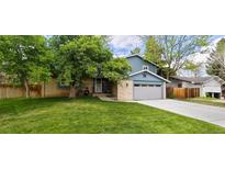 Charming two-story home with a brick facade, blue siding, and a well-manicured lawn at 12175 W 68Th Pl, Arvada, CO 80004