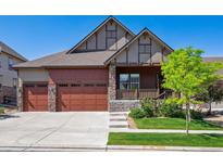 Inviting home featuring a three-car garage, stone accents, manicured lawn and a covered porch in a suburban neighborhood at 24322 E Mineral Dr, Aurora, CO 80016