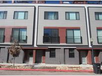 Modern townhome featuring a gray brick facade, second story balconies, and a well-maintained landscaped area at 2350 Tremont Pl # 19, Denver, CO 80205