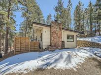 Home exterior with a stone chimney and outdoor seating area at 28251 Meadow Rue Rd, Evergreen, CO 80439