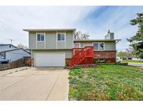 Two-story home features attached garage, red stairs, and brick accents at 8595 Field Ct, Arvada, CO 80005