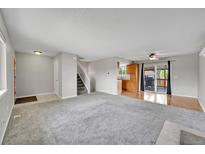 Open-concept living room boasts neutral colors, soft carpet, and sliding glass doors to the deck at 8595 Field Ct, Arvada, CO 80005