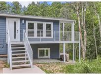 Blue home with white railing, stairs to porch, and windowed door surrounded by trees at 629 Copperdale Ln, Golden, CO 80401
