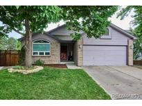 Charming single-Gathering home featuring a well-manicured front yard, mature trees, and a brick-accented facade at 9036 W Wisconsin Ave, Lakewood, CO 80232